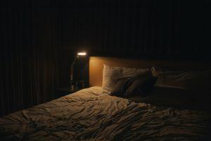 Comodino con lampada accesa in una camera da letto rilassante